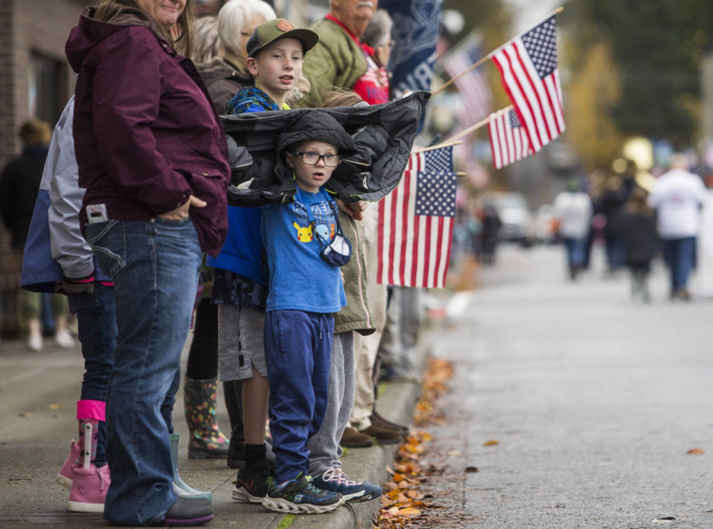 People wave flags and watch the Veterans Day Parade on Thursday, Nov. 11, 2021 in Arlington, Wa. (Olivia Vanni / The Herald)
