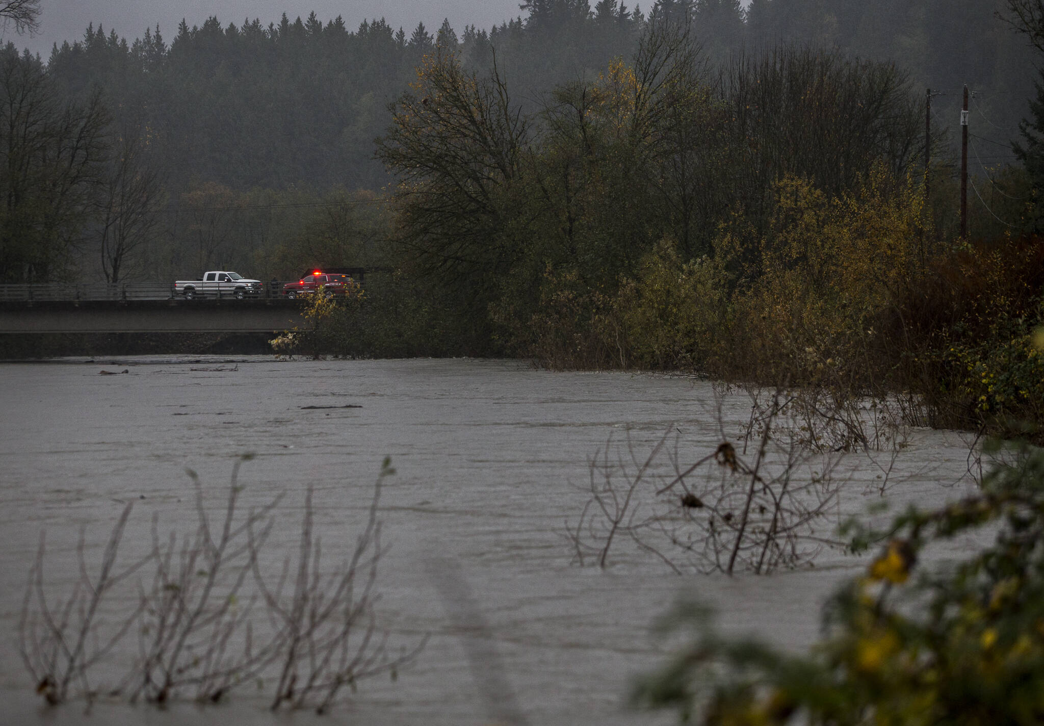 People step out of their vehicles along the Pioneer Highway to look at the rising water in Cook Slough on Friday in Silvana. (Olivia Vanni / The Herald)