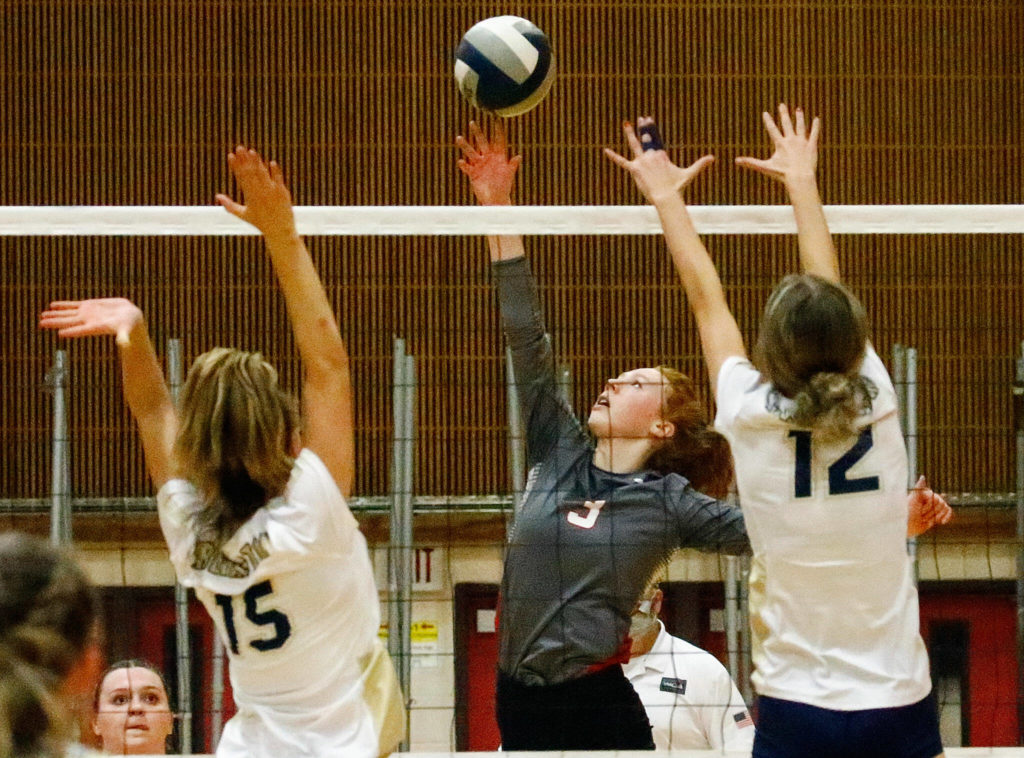 Arlington’s Reese Remle, left, and Arlington’s Ellie Salstrom jump to block kill attempt by Stanwood’s Barrett Anderson Thursday evening during the 3A District volleyball playoffs at Marysville Pilchuck High School on November 11, 2021. (Kevin Clark / The Herald)
