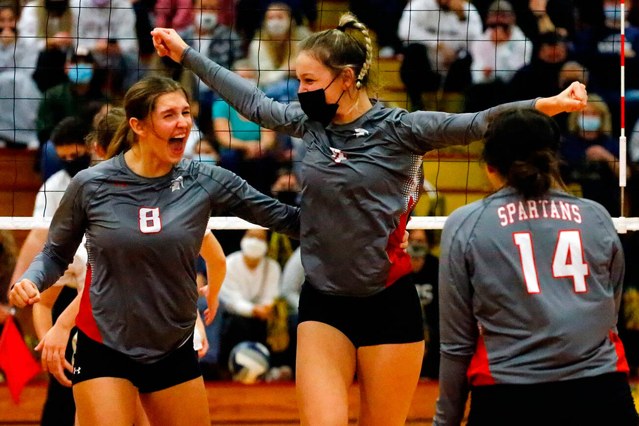 Stanwood's Olivia Rueckert, left to right, Mallory Duffy and Mischa Kessler celebrate a point against Arlington Thursday evening during the 3A District volleyball playoffs at Marysville-Pilchuck High School on November 11, 2021.            
(Kevin Clark / The Herald)