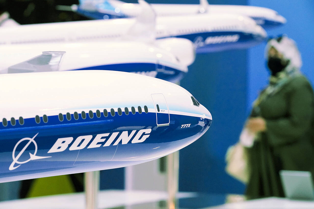 A woman walks by models of Boeing Co. aircraft, including the manufacturer’s new Boeing 777X, at the Dubai Air Show in Dubai, United Arab Emirates on Wednesday. (AP Photo/Jon Gambrell)