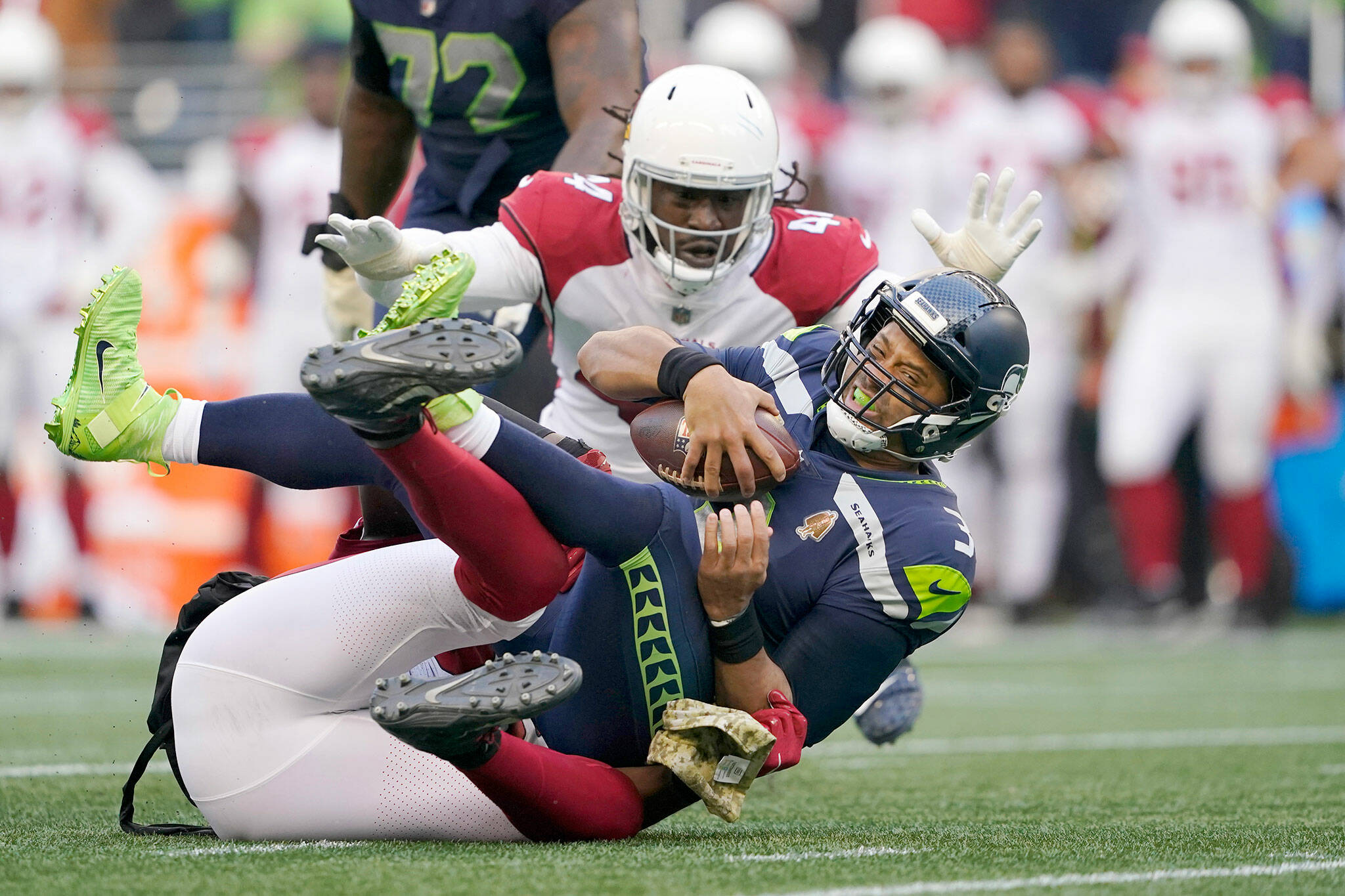 Seattle Seahawks quarterback Russell Wilson is sacked by Arizona Cardinals defender Chandler Jones (bottom) as Markus Golden closes in during the second half of a game Sunday in Seattle. (AP Photo/Ted S. Warren)