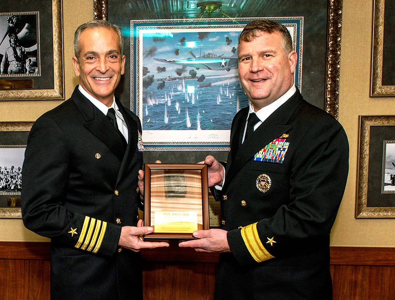 Rear Adm. Christopher Sweeney (right), commander of Puget Sound-based Carrier Strike Group 11, presents Capt. Craig Sicola, commanding officer of the USS Nimitz, with a USS Arizona relic in Bremerton last week. (U.S. Navy/MC3 Justin McTaggart)