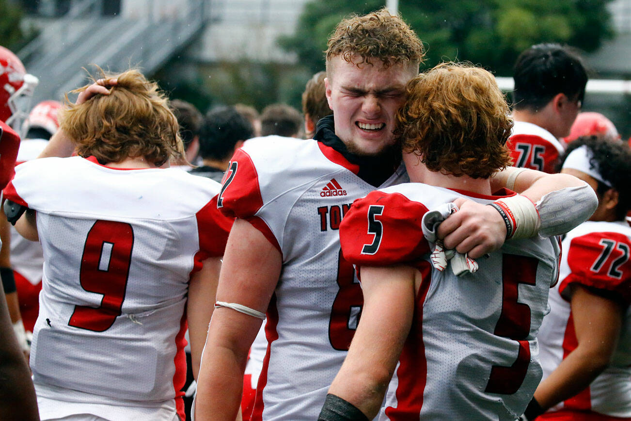 Marysville-Pilchuck's Brayden Rogers, left, and Dylan Carson take comfort after loosing to Bellevue High Saturday afternoon at Memorial Stadium in Seattle on November 27, 2021. The Tomahawks fell to the Wolverines 27-3 ending their playoff run. (Kevin Clark / The Herald)