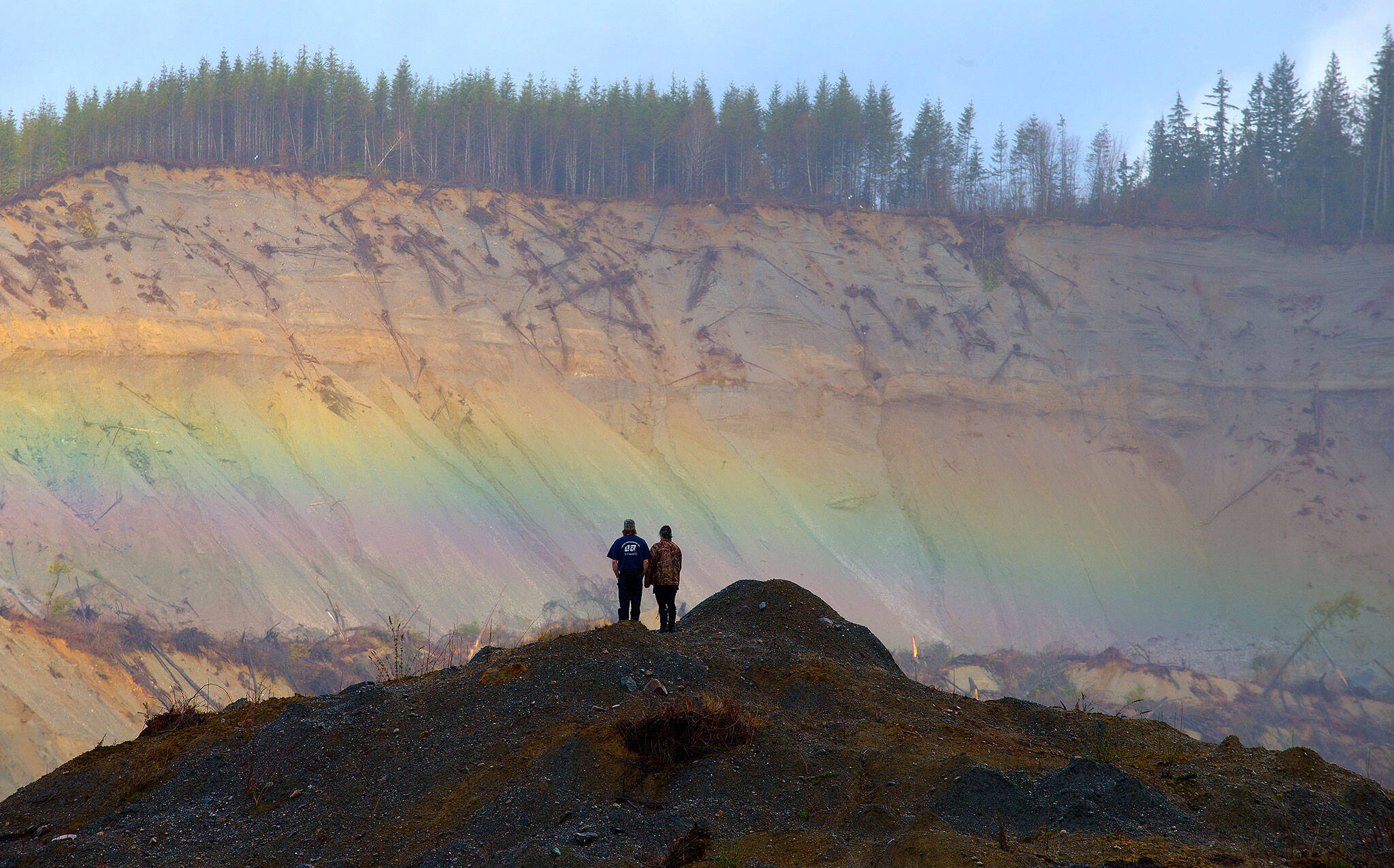A rainbow appears in front of Andy Huestis and Alisha Garvin as they and other families gathered to remember the victims on the third anniversary of the 2014 Oso mudslide on March 22, 2017. Huestis’ sister, Christina Jefferds, and her baby granddaughter, Sanoah Violet Huestis, were among the 43 people killed. (Andy Bronson / Herald file)
