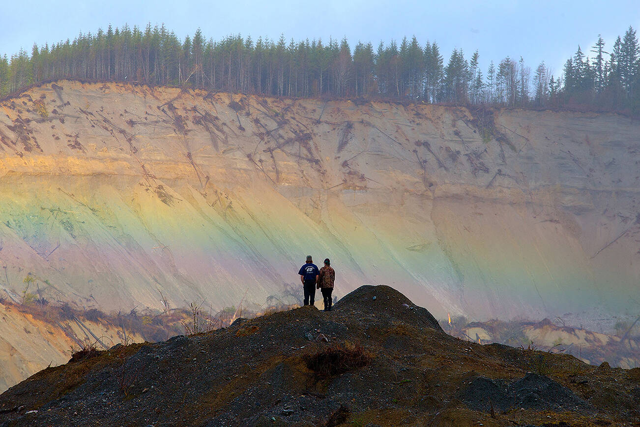 A rainbow appears in front of Andy Huestis and his girlfriend Alisha Garvin as they and other families gather to remember the victims on the third anniversary of the Oso mudslide on Wednesday, March 22, 2017 in Oso, Wa. Huestis' sister, Christina Jefferds, and her baby granddaughter, Sanoah Violet Huestis, were among the 43 people killed in the mudslide.  (Andy Bronson / The Herald)