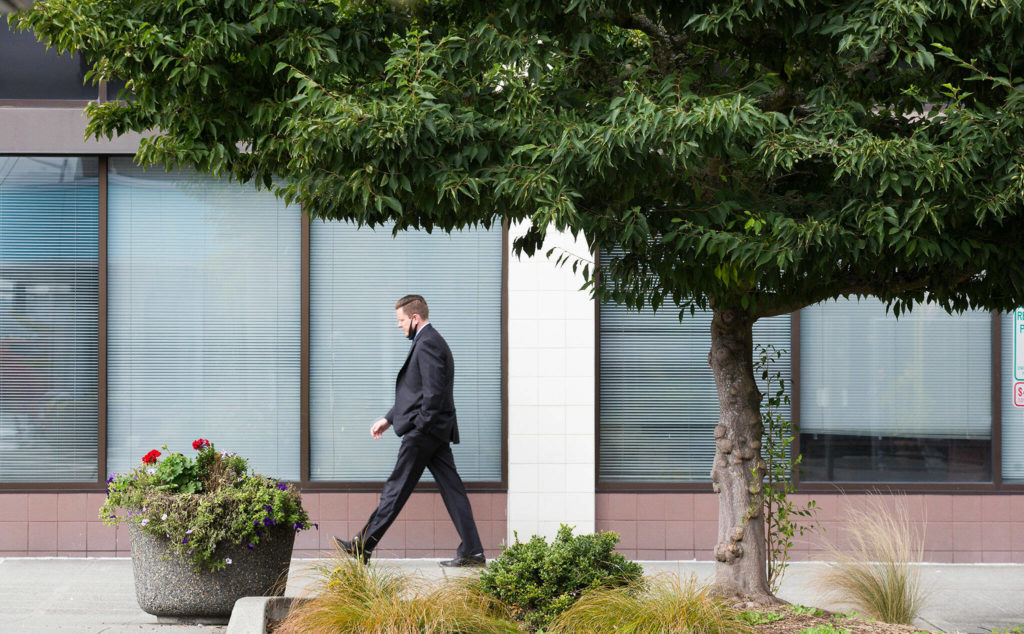 A man walks past a Japanese snowbell tree near Wall and Colby in downtown Everett on Oct. 4. (Andy Bronson / The Herald) 
