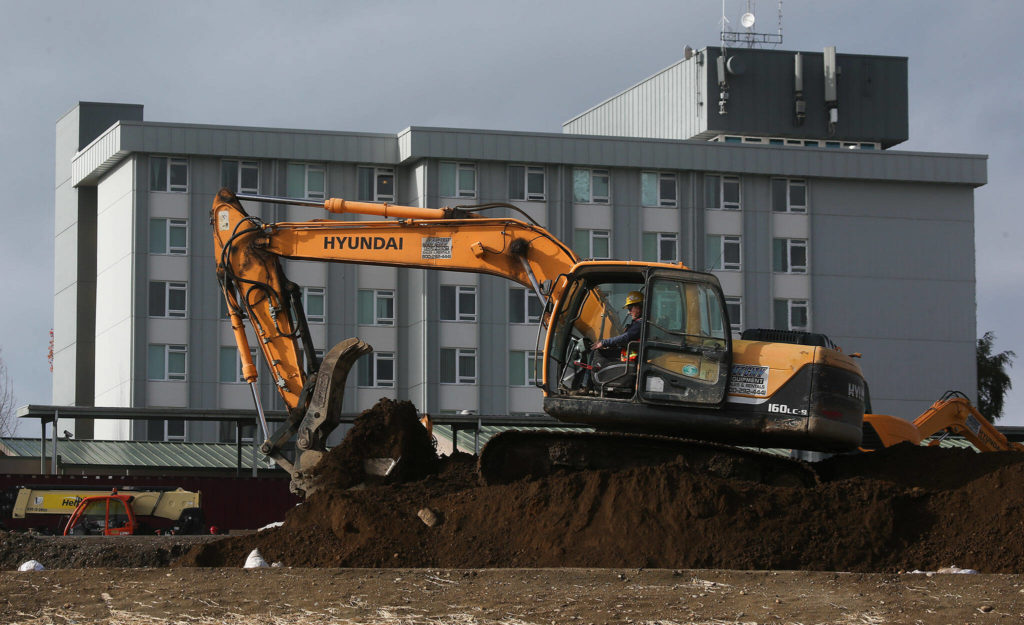 An excavator moves dirt at the Baker Heights project on Wednesday in Everett. (Andy Bronson / The Herald)
