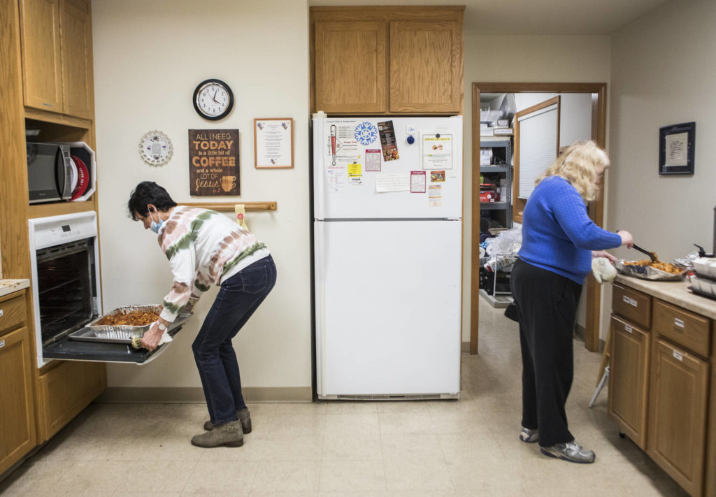 Barbara Schornak (left) and Holly Sullivan (right) heat food for Faith Lutheran Church’s hot meal night Nov. 30 in Everett. (Olivia Vanni / The Herald)

