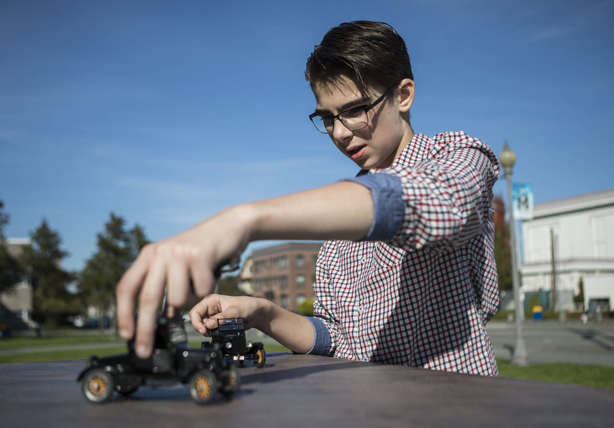Anthony Schmidt works on setting up a scene in front of Everett High School for his photo shoot using forced perspective photography. In the resulting photo, the model car looks life-sized and real. (Olivia Vanni / The Herald)