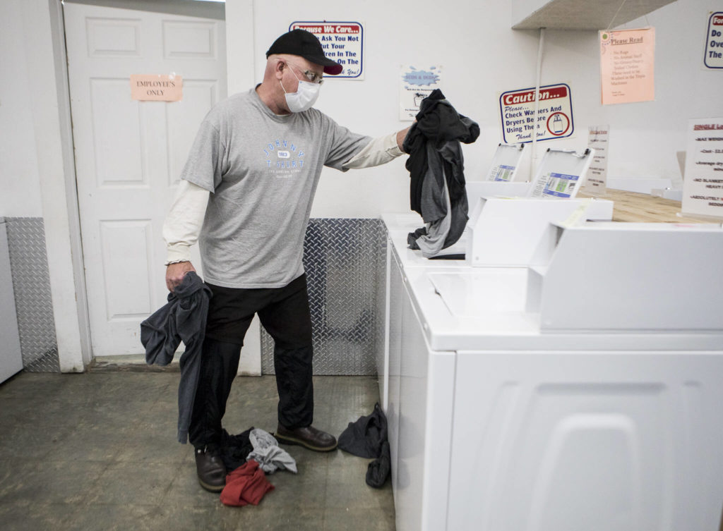 Hank Henry washes clothes at Suds Duds Laundry during North Snohomish County Laundry Outreach on Dec. 1 in Arlington. (Olivia Vanni / The Herald)

