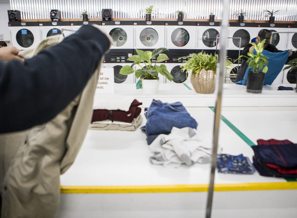 People fold their laundry during North Snohomish County Laundry Outreach on Dec. 1 in Arlington. (Olivia Vanni / The Herald)
