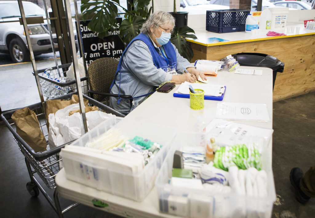 Grama Patty gives out a sticky note to mark a washing machine that is in use during North Snohomish County Laundry Outreach on Dec. 1 in Arlington. (Olivia Vanni / The Herald)

