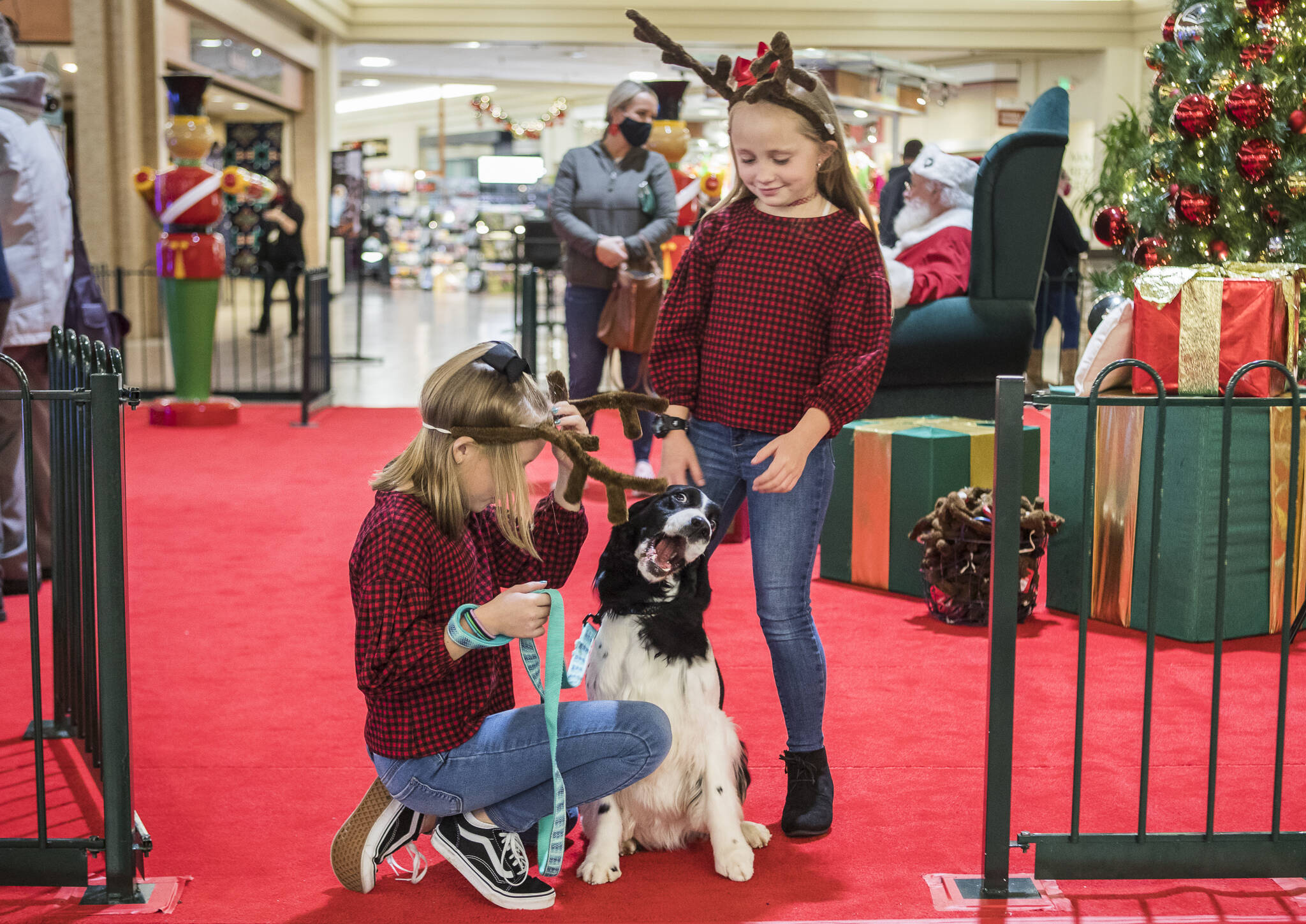 Peyton and Parker Von Kleeck play with their dog Hazy after getting photos with Santa during the Paws With Cause Pet Night at the Everett Mall on Dec. 2. (Olivia Vanni / The Herald)