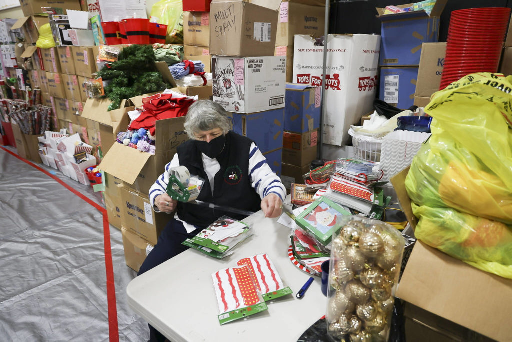 Volunteer Cathy Swain tapes gifts together at the Everett Boys Girls Club Christmas House on Monday. (Andy Bronson / The Herald)
