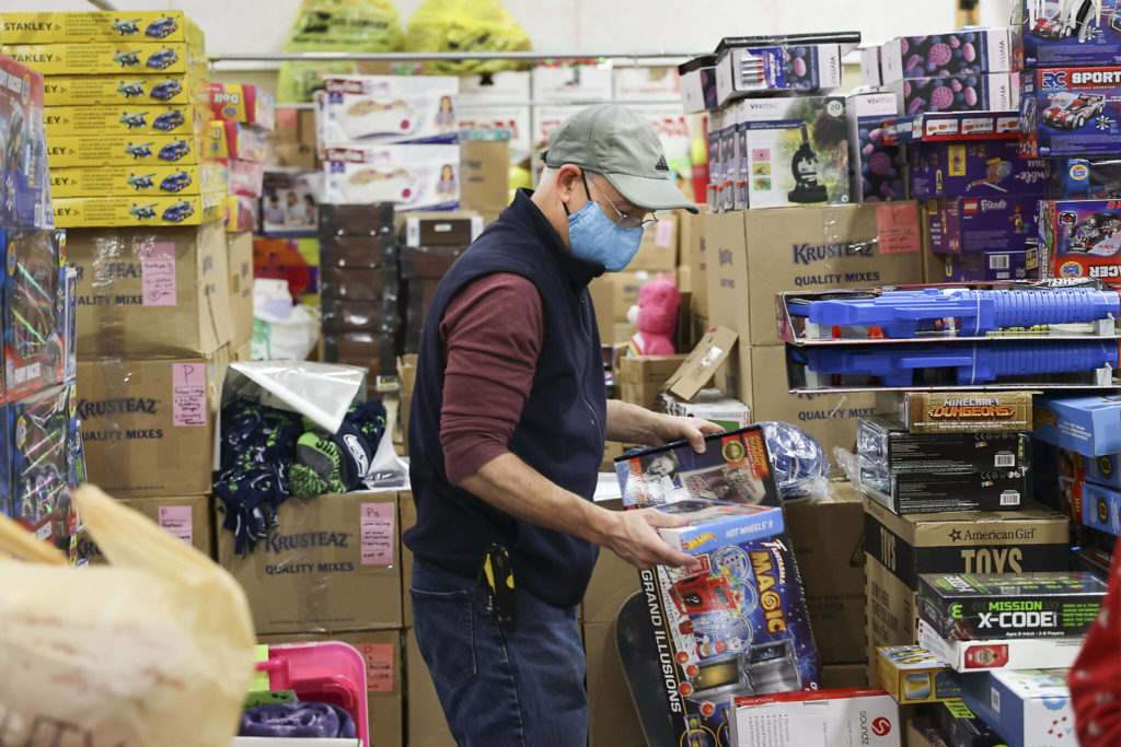 Volunteer Jim McFarland organizes gifts at the Everett Boys Girls Club Christmas House on Monday. (Andy Bronson / The Herald)

