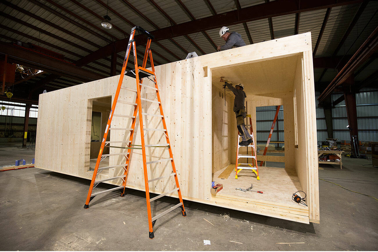 Carpenters from America and Switzerland build the first "modular home" made from cross-laminated timber, inside a warehouse on Marine View Drive on Tuesday, Nov. 30, 2021 in Everett, Washington.  (Andy Bronson / The Herald)