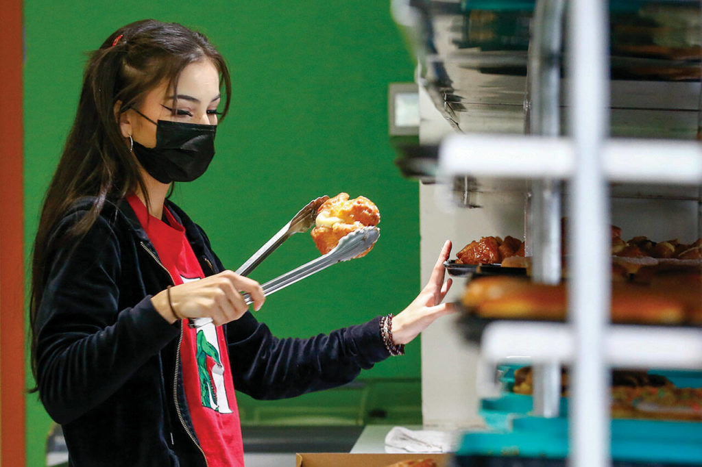 Charlize Weiss fills an order at Donut Factory in Lynnwood. (Kevin Clark / The Herald)
