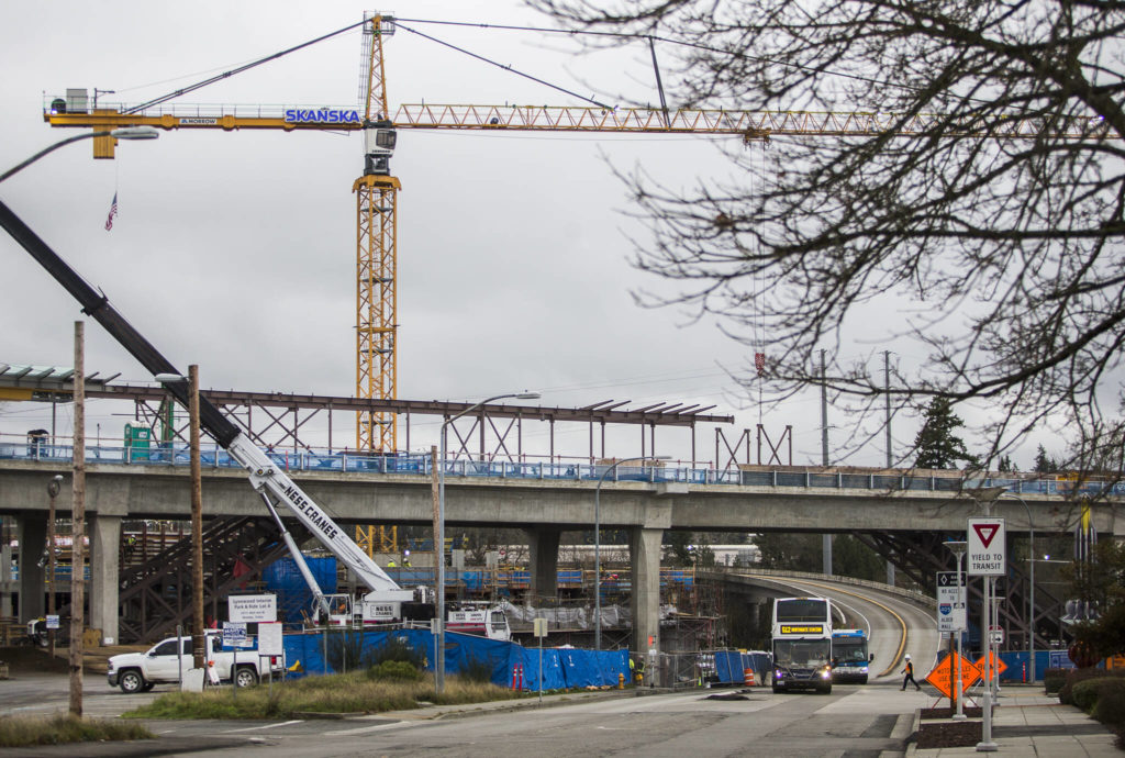 A construction worker crosses the street Friday as two buses pull into the Lynnwood Transit Center in Lynnwood. (Olivia Vanni / The Herald)
