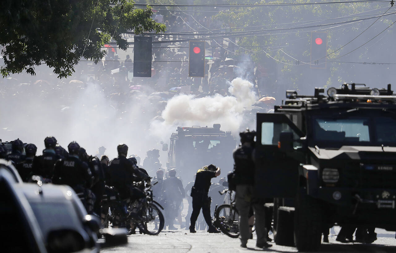 In this July 25, 2020 photo, smoke rises as police clash with protester during a Black Lives Matter protest near the Seattle Police East Precinct headquarters. (AP Photo/Ted S. Warren, File)