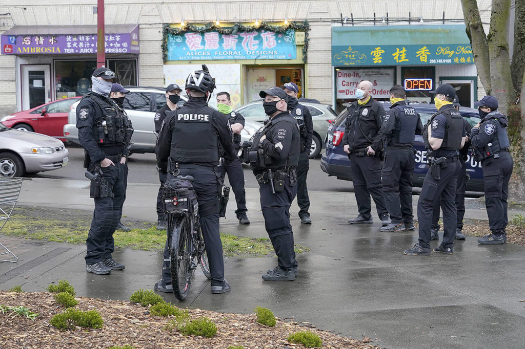 Seattle Police officers confer after taking part in a public roll call at Hing Hay Park in Seattle’s Chinatown-International District on March 18, 2021. Seattle’s police department is having detectives and non-patrol staff respond to emergency calls because of a shortage of officers union leaders fear will be made worse by COVID-19 vaccine mandates. (AP Photo/Ted S. Warren, File)
