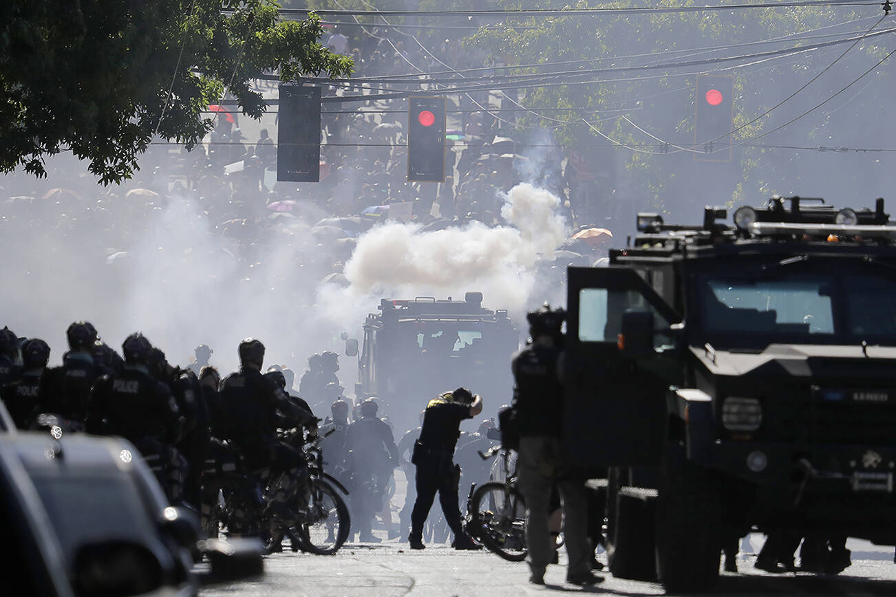 FILE - In this July 25, 2020, file photo, smoke rises as police clash with protester during a Black Lives Matter protest near the Seattle Police East Precinct headquarters in Seattle. Mayors, county executives or even the governor would have to give their approval before police could use tear gas to quell riots under a compromise reached in the Washington Legislature. A conference committee of the House and Senate met Thursday, April 22, 2021, to reconcile versions of a police tactics bill already approved by each chamber. (AP Photo/Ted S. Warren, File)