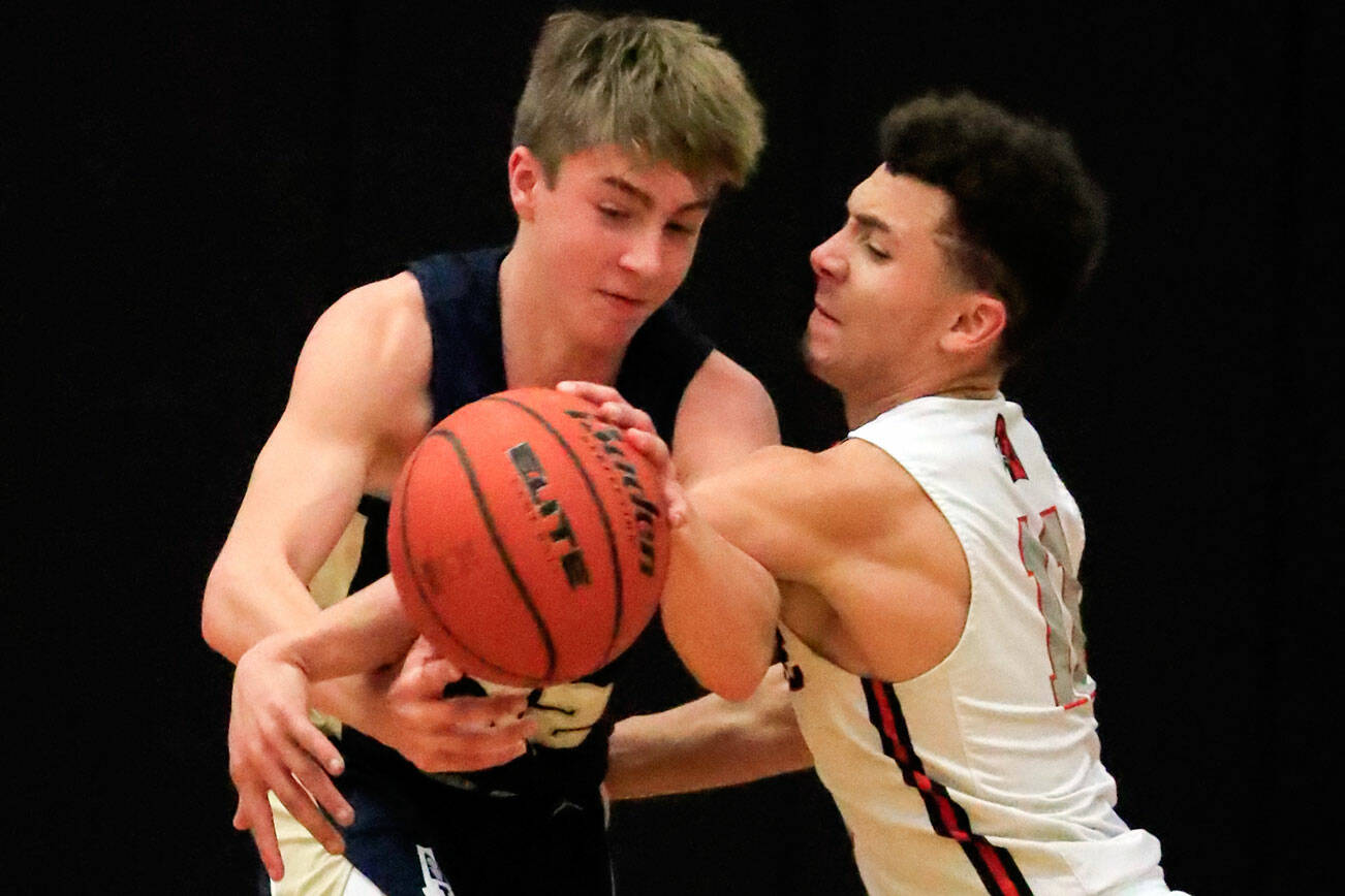 Mountlake Terrace's Chris Meegan, right, reaches in and fouls Arlington's Leyton Martin Friday evening at Mountlake Terrace High School on December 10, 2021. The Eagles won 70-55. (Kevin Clark / The Herald)