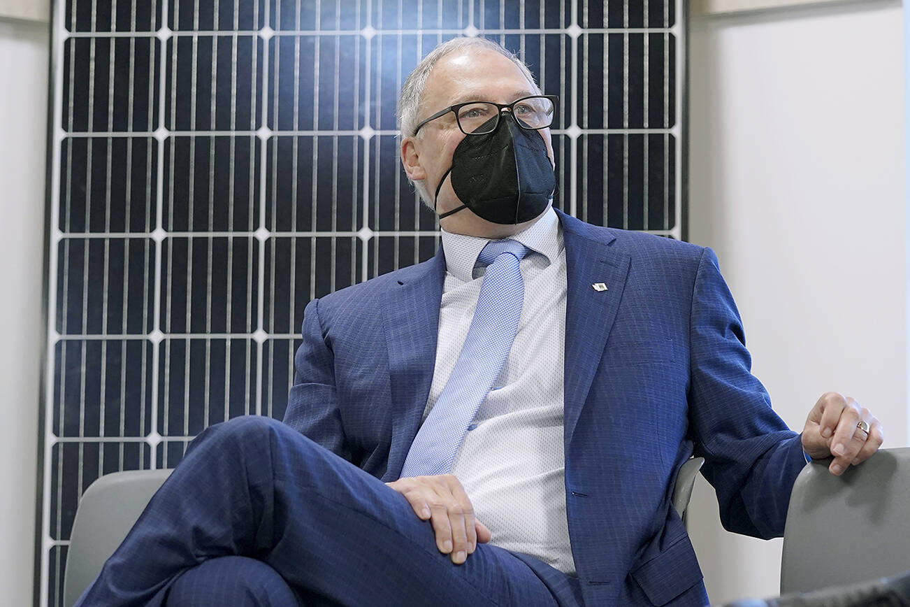 Washington Gov. Jay Inslee sits in front of a solar panel after speaking, Monday, Dec. 13, 2021, at a news conference in Olympia, Wash. Inslee announced several climate-related proposals for the 2022 legislative session, including a plan to offer rebates on the purchase of new and used electric vehicles for qualified buyers. (AP Photo/Ted S. Warren)