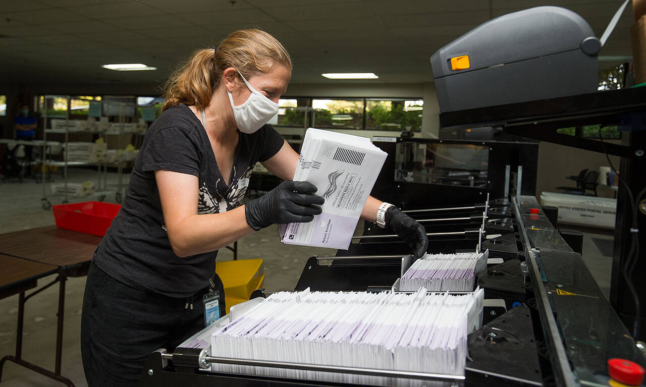 Catherine Berwicks loads ballots into a tray after scanning them at the Snohomish County Elections Ballot Processing Center Aug. 4, 2020, in Everett. (Andy Bronson / Herald file)