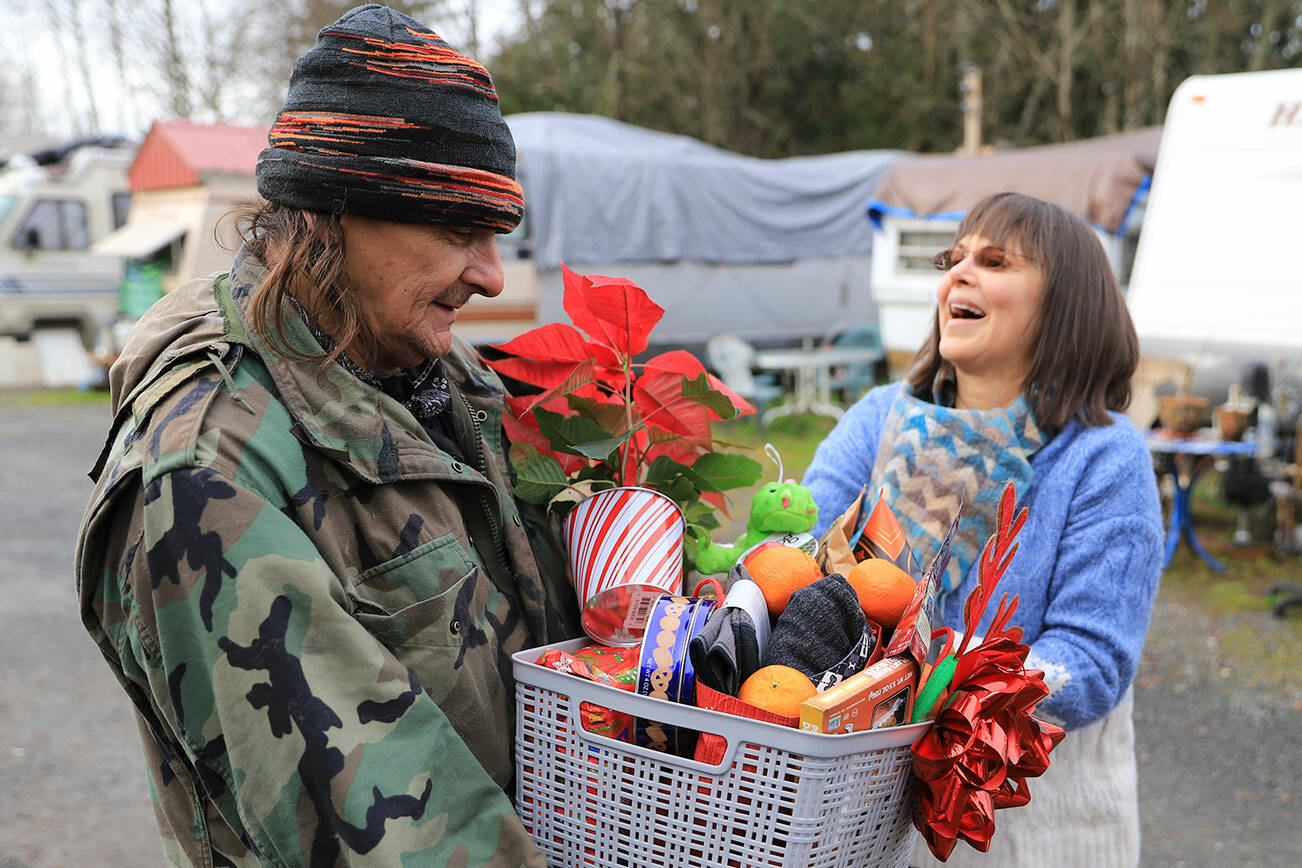 Tony Cody receives a gift basket from Penelope Protheroe Friday afternoon in Granite Falls on December 17, 2021.  (Kevin Clark / The Herald)