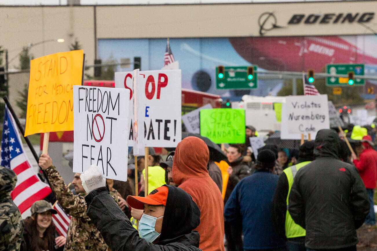 People hold signs in protest of the vaccine mandate after Boeing announced it would terminate workers who do not comply on Friday, Oct. 15, 2021 in Everett, Wa. (Olivia Vanni / The Herald)