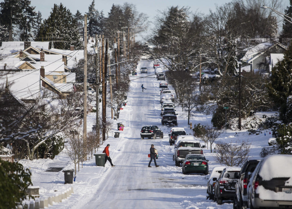 Cars and pedestrians carefully navigate the ice and snow along Grand Avenue on Monday in Everett. (Olivia Vanni / The Herald)
