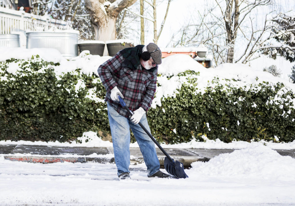 Tim Knopf shovels out a parking spot from his family coming to visit Monday in Everett. (Olivia Vanni / The Herald)
