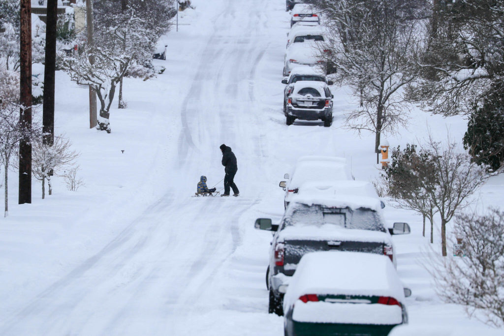 Cars and streets are blanketed in snow Sunday afternoon in Everett. (Kevin Clark / The Herald)
