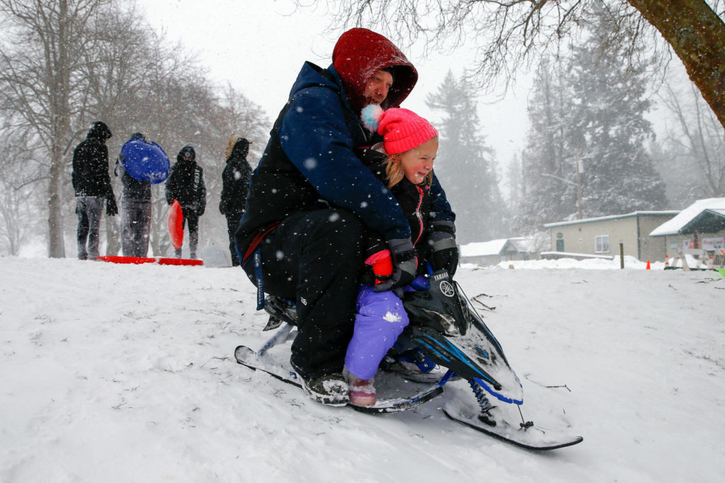 Dustin Curtis and Kyla Curtis, 5, take to the slopes of Forest Park on Sunday afternoon in Everett. (Kevin Clark / The Herald)
