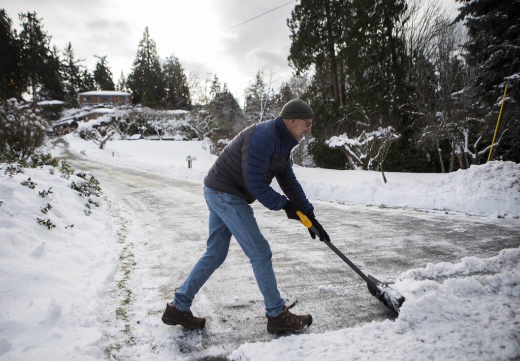 Tim Pfahl finishes shoveling his long driveway for the third time this week on Thursday in Everett. (Olivia Vanni / The Herald)
