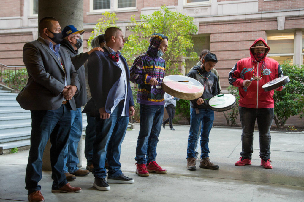 Hazen Shopbell (left) and Anthony Paul (third from left) listen to a drum circle play before a hearing at Skagit County Superior Court on Oct. 25 in Mount Vernon. (Andy Bronson / The Herald)
