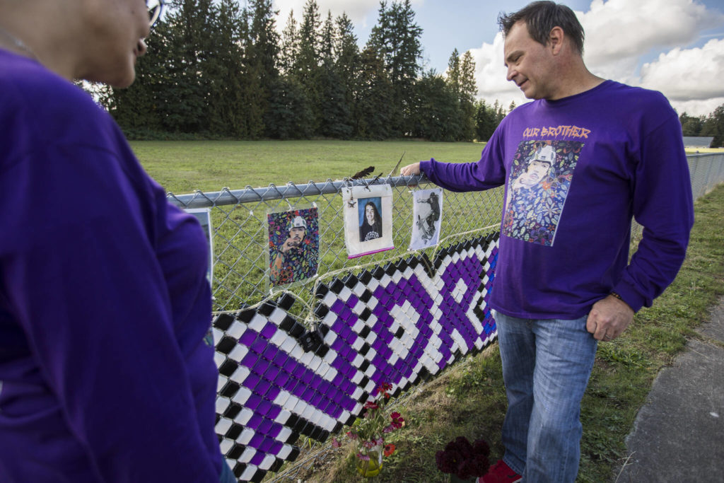 Chad Hofland and his wife, Xochitl, look at a photograph of their son Andre, 17, at a memorial along 116th Street on Oct. 7 in Marysville. Andre was was shot and killed in robbery on Jan. 5, 2021. (Olivia Vanni / The Herald)
