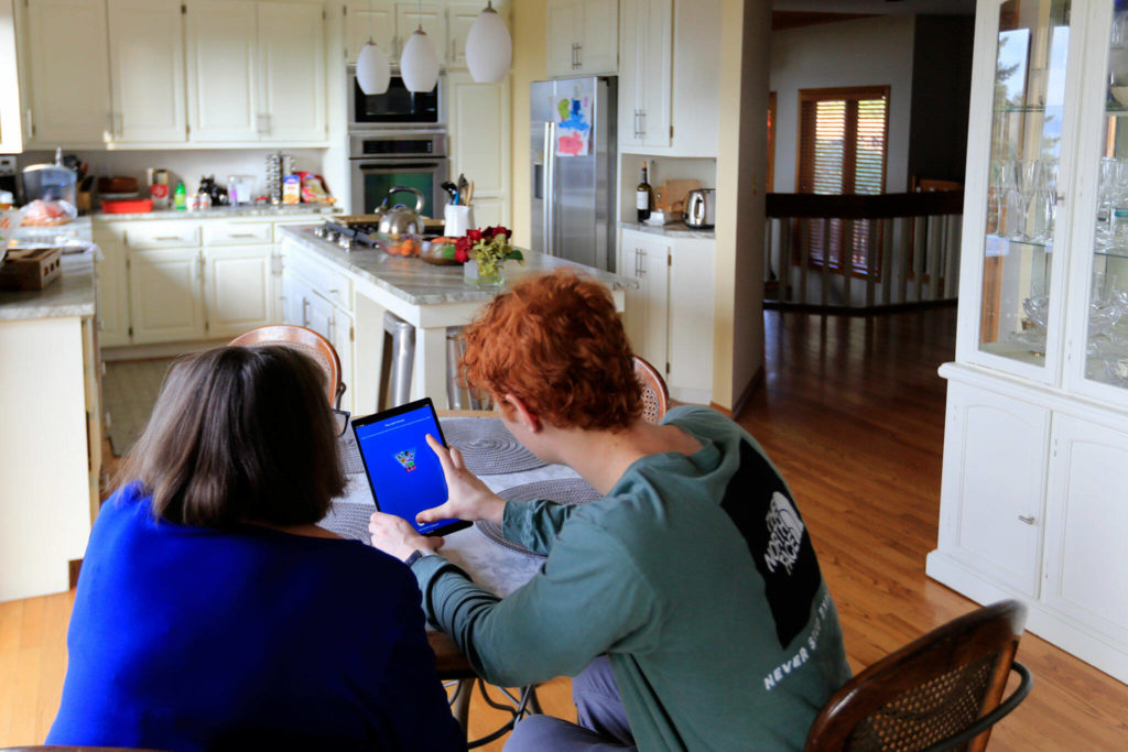 Jack Rice (left) gives his grandmother Carolyn Rice a tutorial on her new tablet. (Kevin Clark / The Herald)
