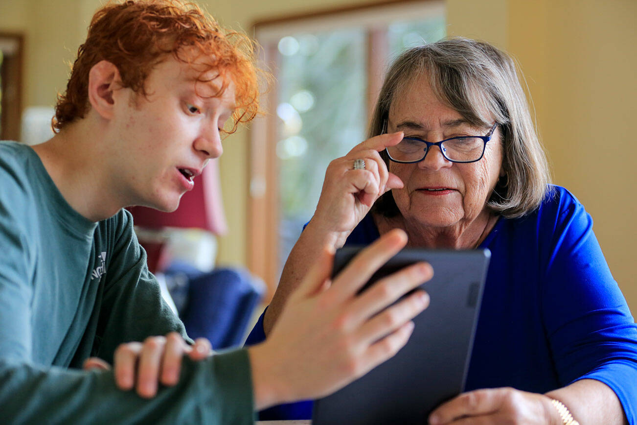 Jack Rice, left, gives his grandmother Carolyn Rice, a tutorial on her new tablet Saturday afternoon in Edmonds on November 20, 2021.  (Kevin Clark / The Herald)