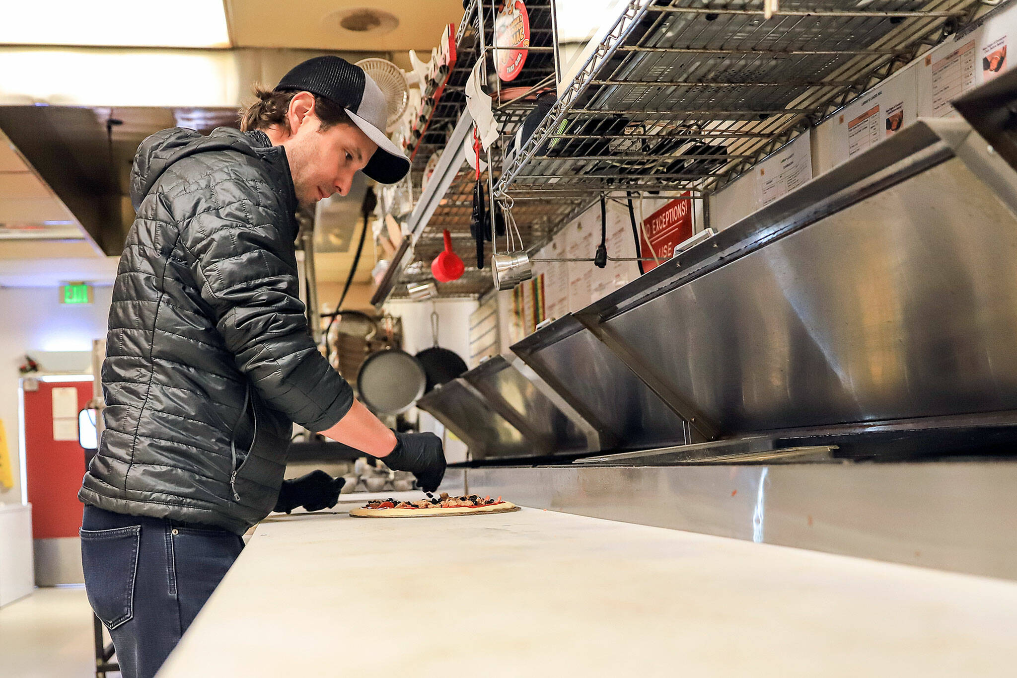 Bruce Olson assembles a pizza at Alfy’s on Evergreen Way in Everett on Dec. 23. (Kevin Clark / The Herald)