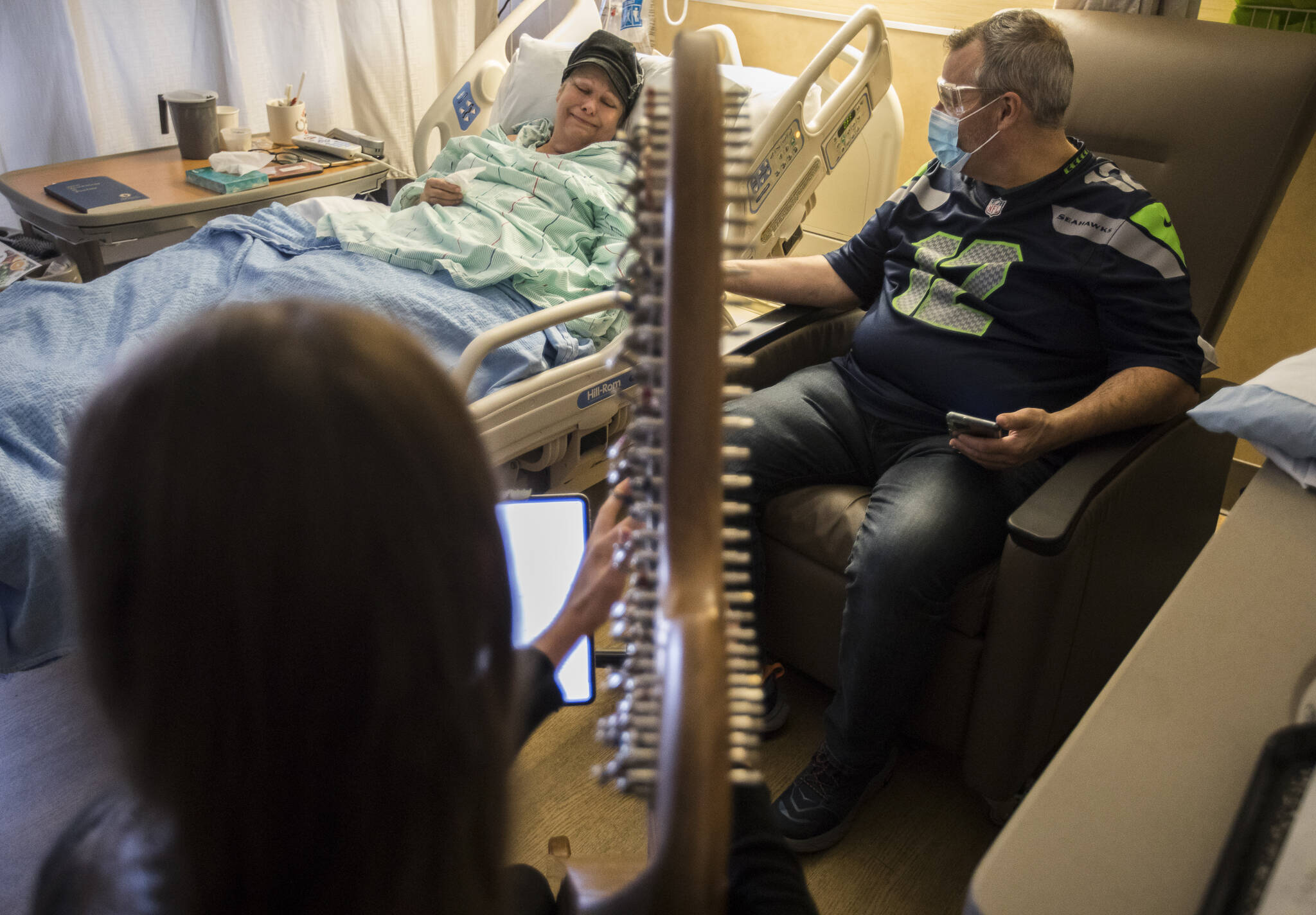 Shelly Holmgren becomes emotional while listing to April Mitchell play her harp at Providence Regional Medical Center Everett on Dec. 17, 2021. (Olivia Vanni / The Herald)