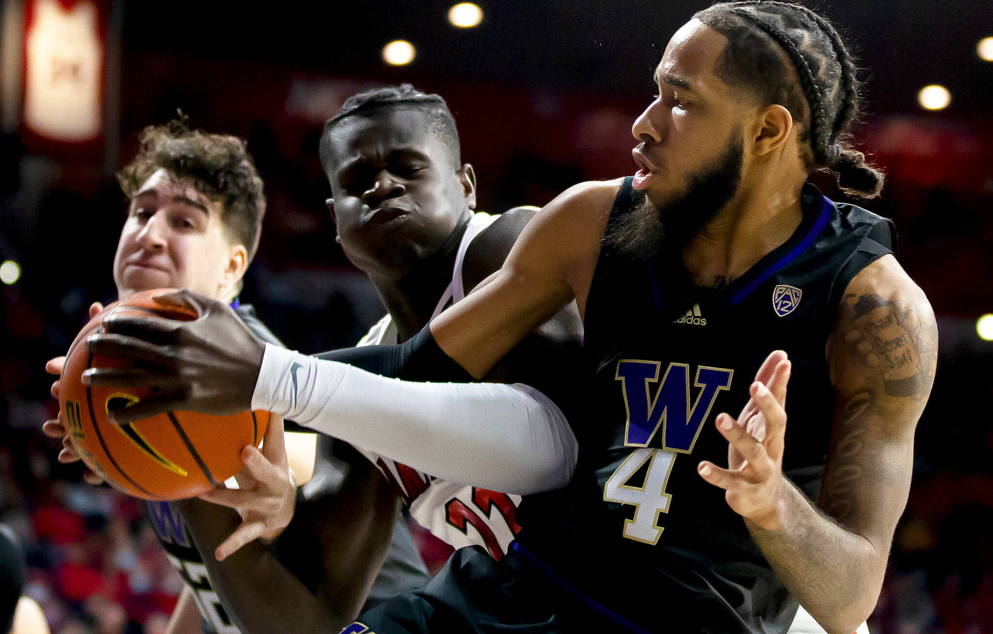 Washington guard PJ Fuller (4) and Arizona center Oumar Ballo (11) fight for a possession of a rebound during the first half of a game in Tucson, Ariz., Monday, Jan. 3, 2022. (Rebecca Sasnett/Arizona Daily Star via AP)