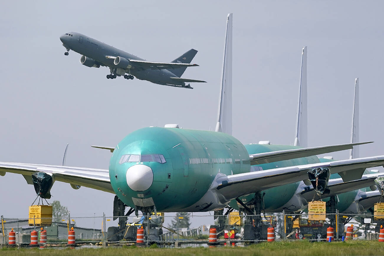 FILE - A U.S. Air Force KC-46A Pegasus jet takes off on April 23, 2021, near a line of Boeing 777X airplanes parked nose to tail on an unused runway at Paine Field, near Boeing's production facility in Everett, Wash. Boeing said Friday, Dec. 17, 2021 that it's suspending a company COVID-19 vaccination mandate for all U.S.-based employees. (AP Photo/Elaine Thompson, File)