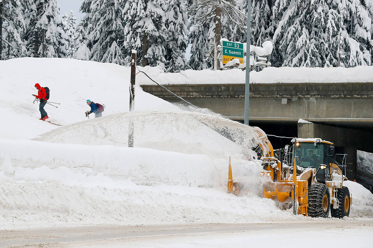 A Washington Department of Transportation snowblower clears the road under I-90 at Summit West as backcountry skiers head up the Pacific Crest Trail after a heavy snowfall at Snoqualmie Pass. (Jennifer Buchanan/The Seattle Times via AP)
