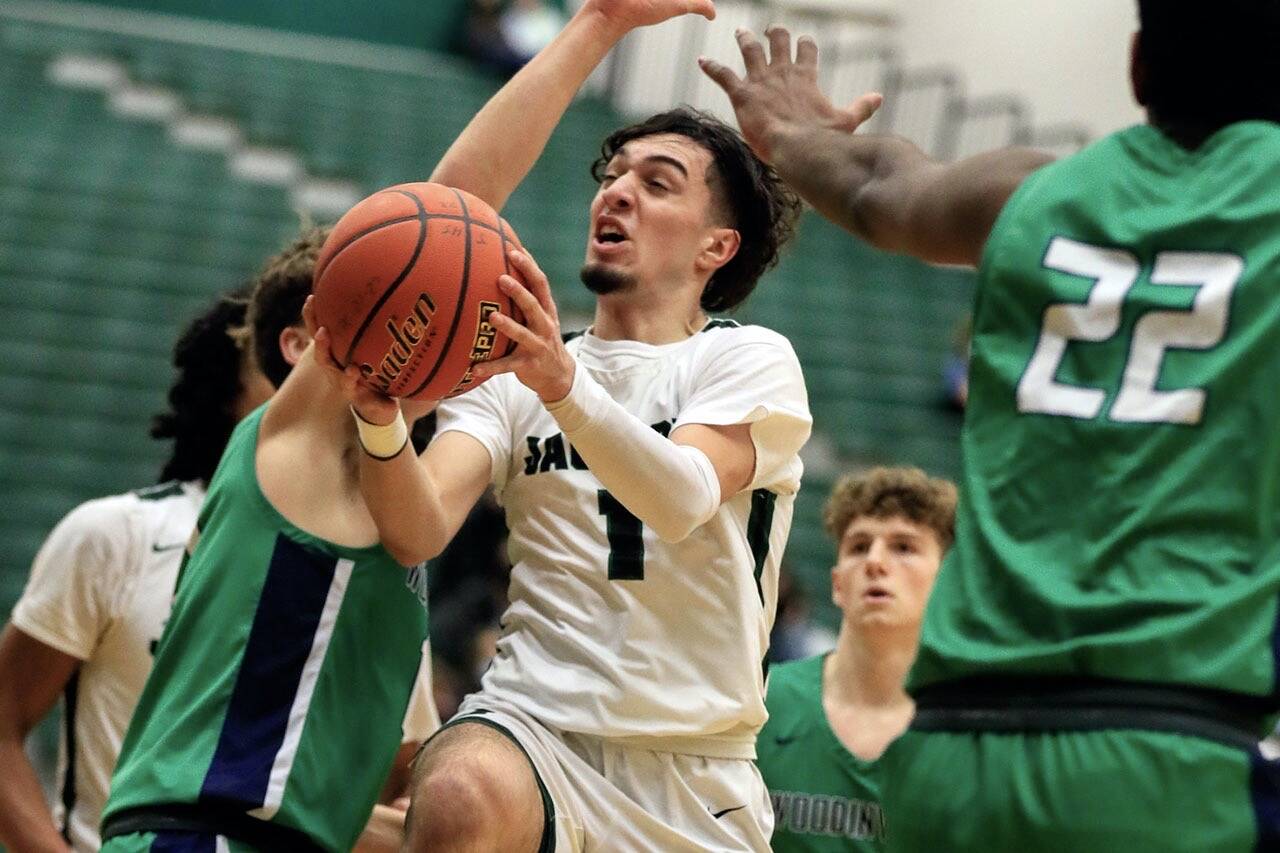 Jackson's Drilon Veliu splits the defense of Woodinville's Ryan Roth, left, and Akhil Damidi at Jackson High School Wednesday evening in Mill Creek, Washington on January 5, 2022. The Timberwolves won 76-57. (Kevin Clark / The Herald)