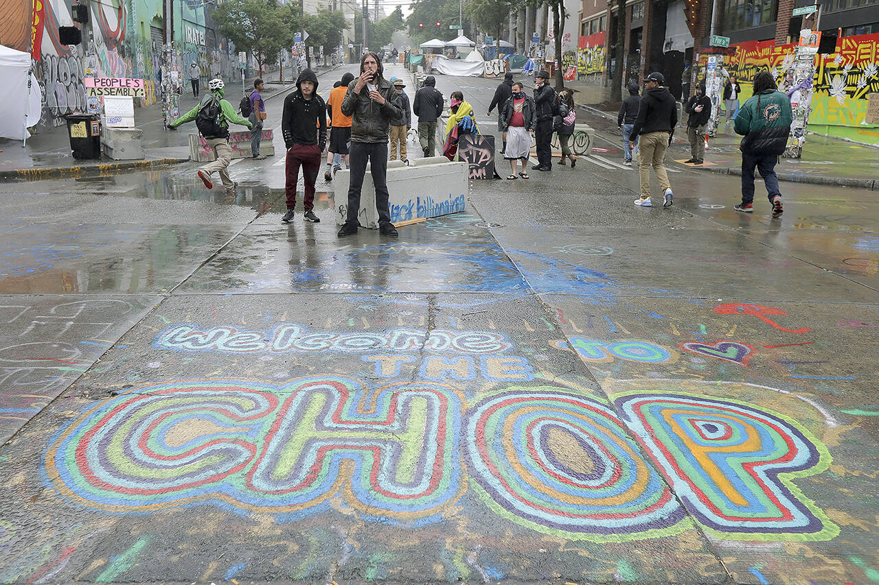 A sign on the street reads “Welcome to the CHOP” as protesters stand near barricades at the CHOP (Capitol Hill Occupied Protest) zone in Seattle on June 30, 2020. (AP Photo/Ted S. Warren, File)