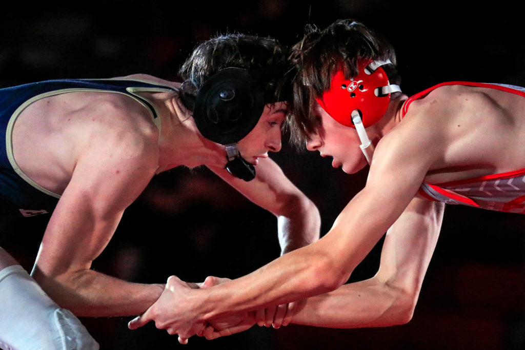 Arlington’s David Forslof (left) faces on with Stanwood’s Lane Ovenell in the 132-pound weight class at Stanwood High School on Thursday evening. (Kevin Clark / The Herald)
