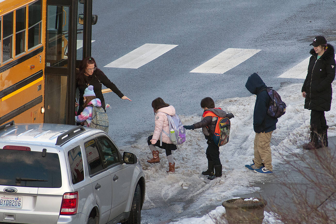 Kids board a school bus Tuesday morning in Everett. (Sue Misao / The Herald) Jan. 4, 2022