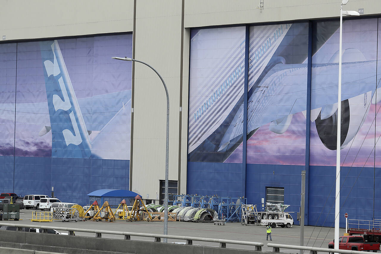 In this 2020 photo, a worker walks near a mural of a Boeing 777 airplane at the company’s manufacturing facility in Everett. (AP Photo/Ted S. Warren, File)